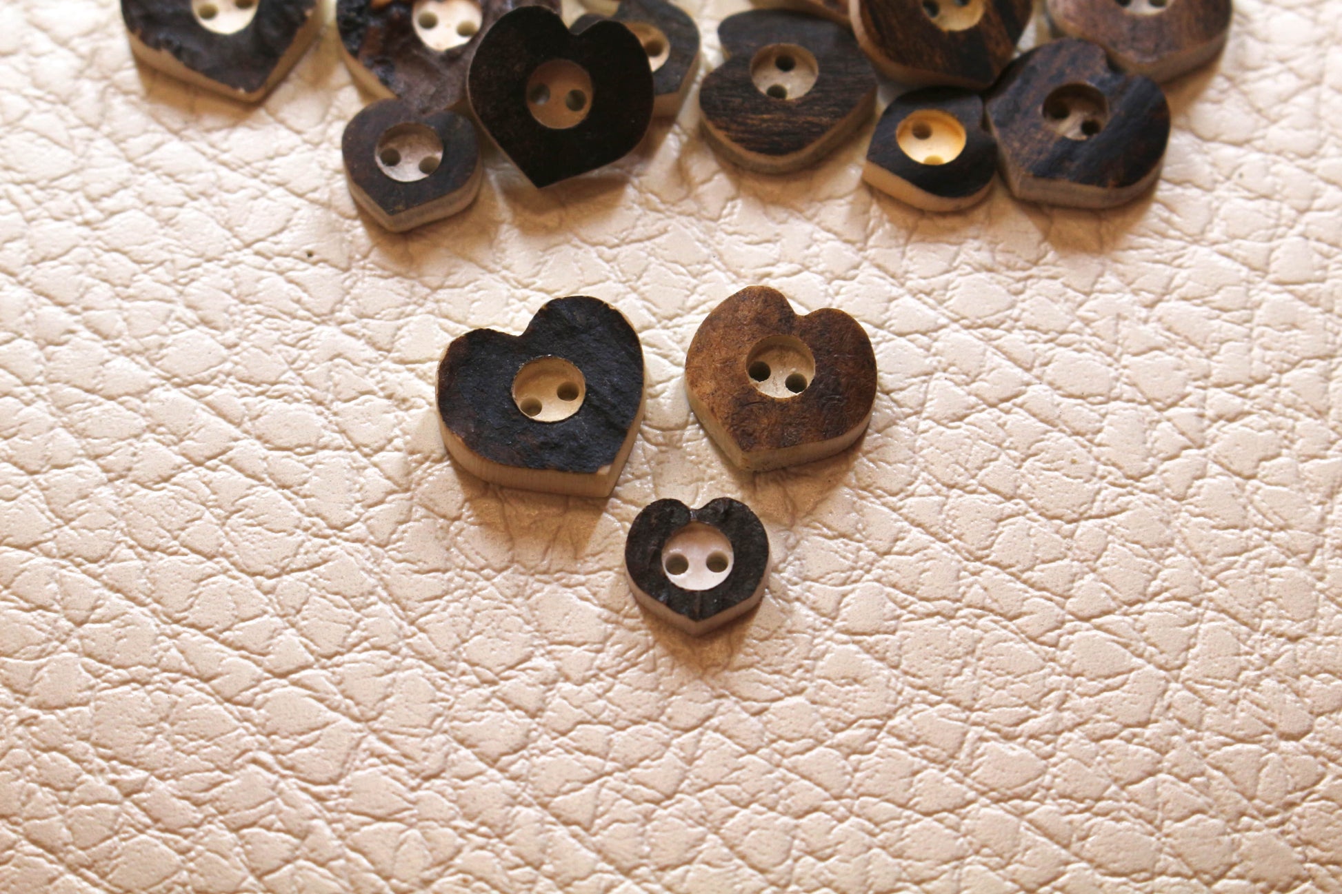 Deer antler buttons shaped like hearts with center drilled in circle around holes