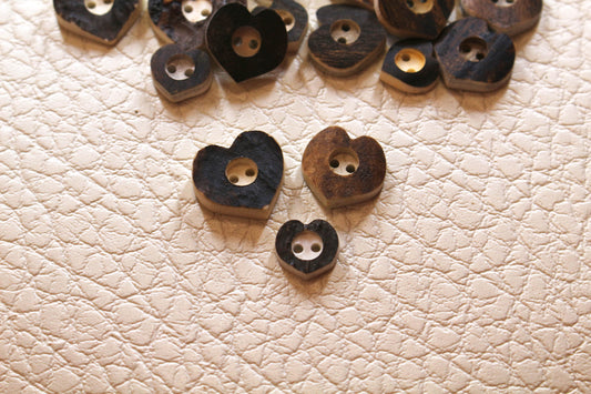 Deer antler buttons shaped like hearts with center drilled in circle around holes